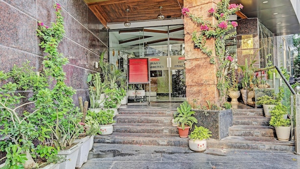 A hotel entrance with a stone staircase, potted plants, and a sign for 'IHAAN SIDENCY.'