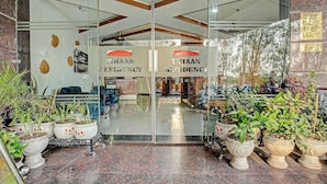 A hotel entrance with glass doors, potted plants, and a sign reading 'VHAAN RESIDENCY'.