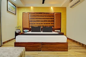 A hotel room with a large bed, wooden headboard, bedside tables, and a small potted plant.