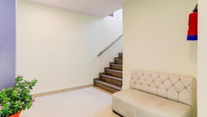 A staircase leading to a landing, a beige sofa, and a potted plant. - Saver Double Hotel Parijat (Lucknow)