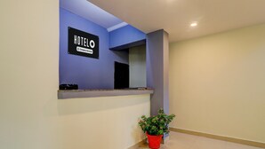 A hotel reception area with a blue wall, a reception desk, a potted plant, and a sign that reads 'HOTELO'. - Saver Double Hotel Parijat (Lucknow)