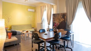 A modern living room with a sofa, coffee table, and dining table with chairs. - Artline Residence in Acropolis District (Athens)