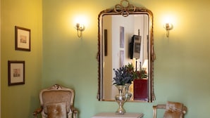 A room with a mirror, two chairs, a small table, and a red rug. - Artline Residence in Acropolis District (Athens)