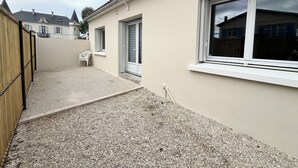 Ein Wohngebäude mit Kiesweg, einer weißen Tür und einem Fenster mit weißem Rahmen.