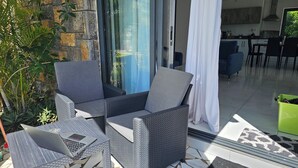 A patio with wicker furniture, a laptop, and a green trash bin. - Marvelous 3-bedroom apartment with AC in Grand Baie (Grand Baie)
