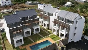 A modern multi-story residential building with balconies, a swimming pool, and a well-maintained garden. - Marvelous 3-bedroom apartment with AC in Grand Baie (Grand Baie)