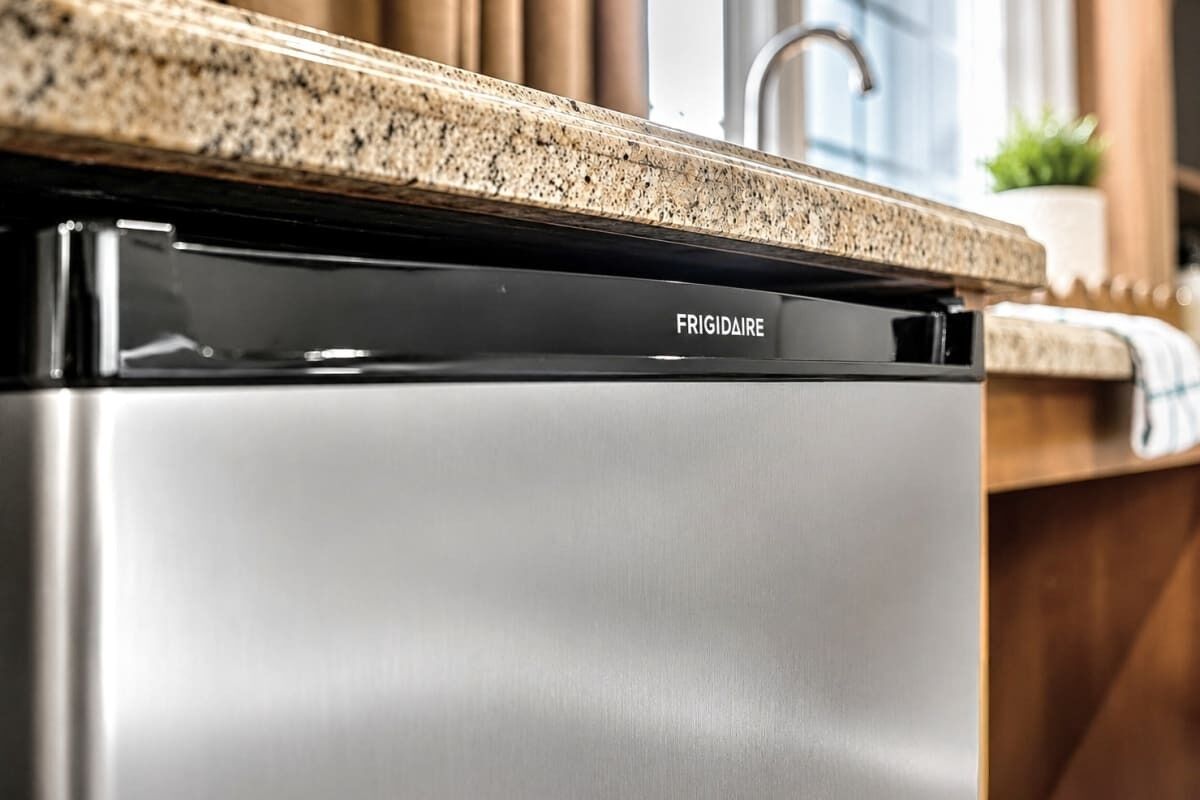 Una cocina con electrodoméstico de acero inoxidable, marca FRIGIDAIRE, y encimera de granito.