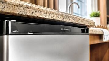 Una cocina con electrodoméstico de acero inoxidable, marca FRIGIDAIRE, y encimera de granito.