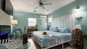 A bedroom with a bed, a ceiling fan, a TV, and a nightstand.
