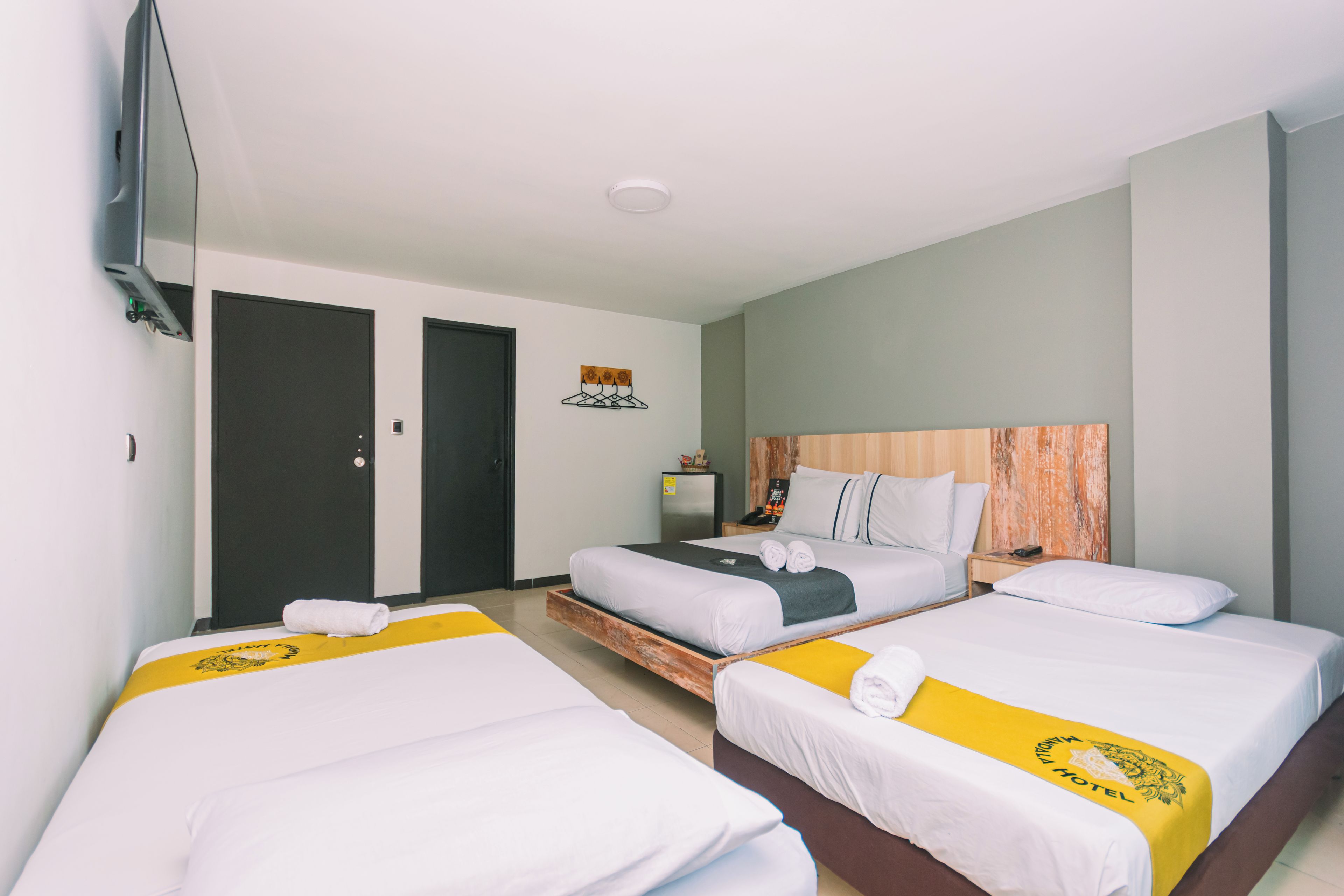 Une chambre d’hôtel avec trois lits, une télévision, une petite table et une porte.