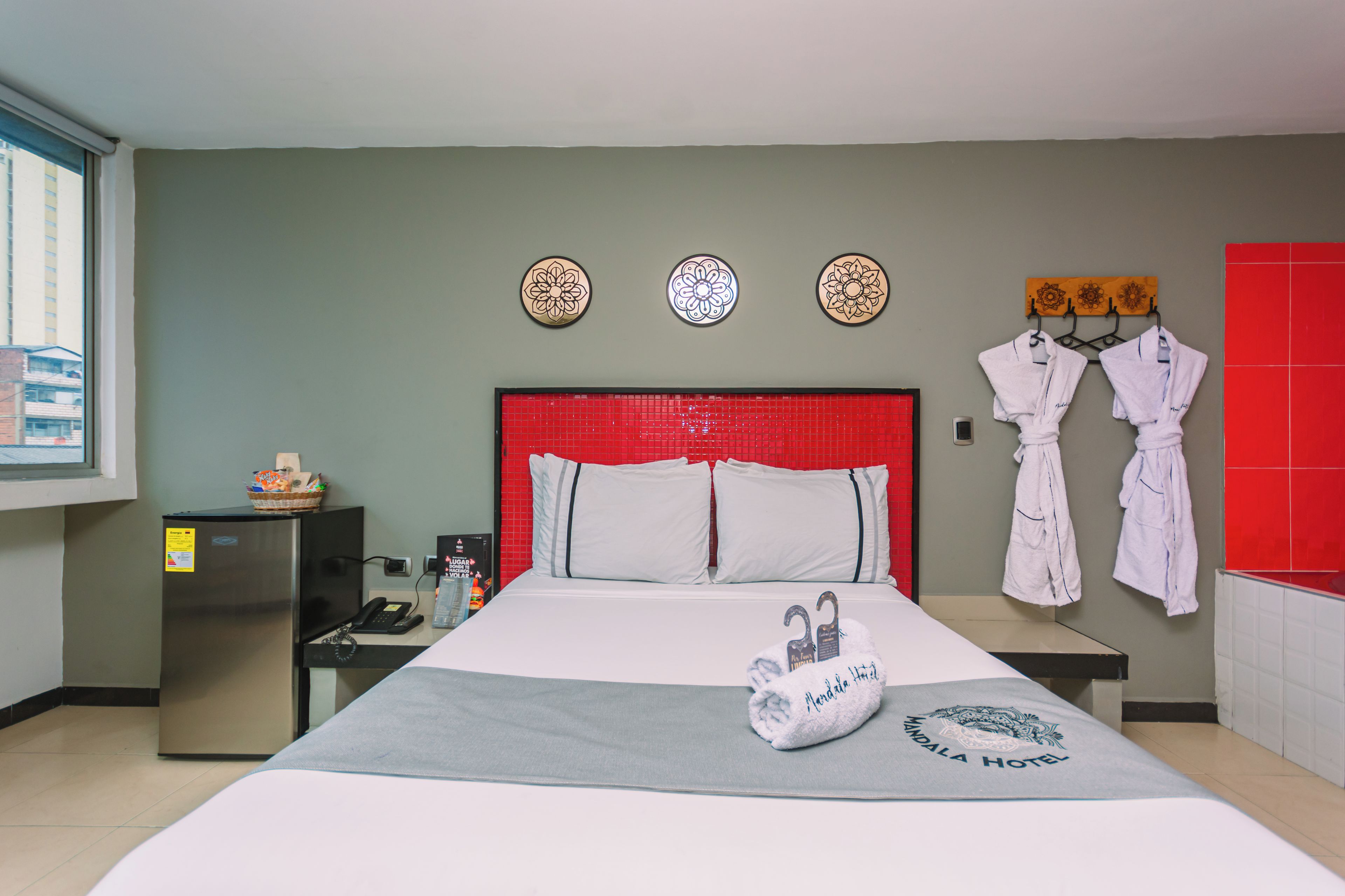 Une chambre d’hôtel avec un lit, un petit bureau, un réfrigérateur et une fenêtre.