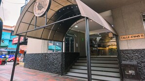 A hotel entrance with a covered walkway, steps leading to the entrance, and a street sign. - Mandala Medellín Centro By Gyc Hotels (Medellín)
