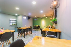 A restaurant interior with multiple tables and chairs, a green accent wall, and a sign indicating the name. - Mandala Medellín Centro By Gyc Hotels (Medellín)