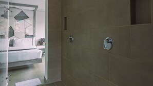 A modern bathroom with a shower, a glass door leading to a bedroom, and a tiled floor. - Mandala Medellín Centro By Gyc Hotels (Medellín)