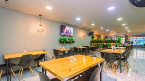 A restaurant with multiple tables and chairs, a TV mounted on the wall, and potted plants. - Mandala Medellín Centro By Gyc Hotels (Medellín)
