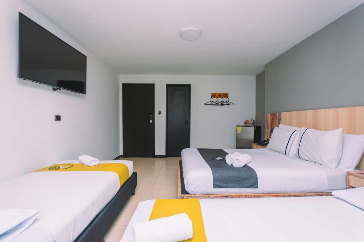 Una habitación de hotel con dos camas, televisión, puerta y una mesita.