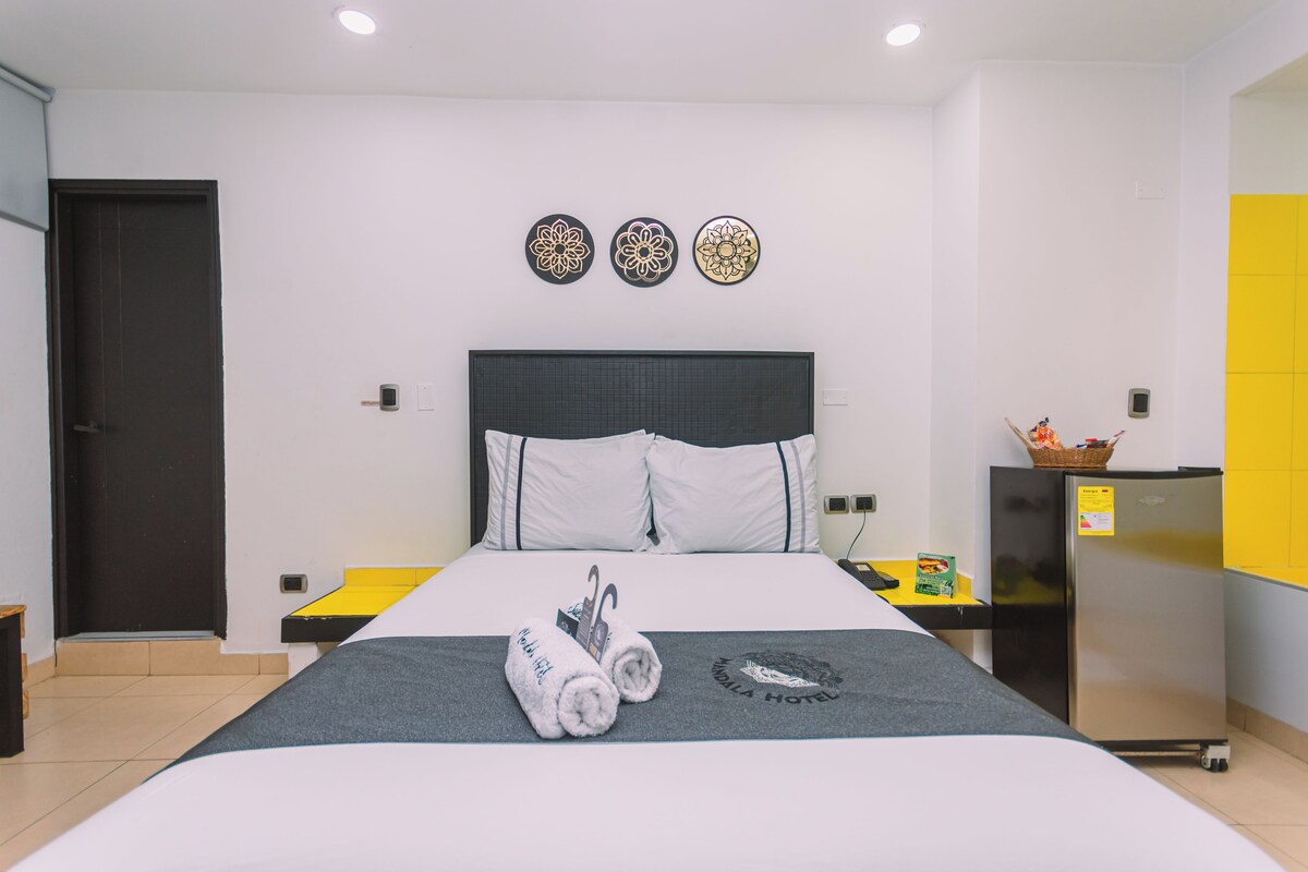 Una habitación de hotel con una cama, una mesita, un refrigerador y decoración en la pared.
