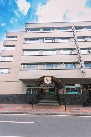 Un hotel de varios pisos con un llamativo letrero 'HOTEL', una entrada curva y una escalera visible que conduce a la entrada.