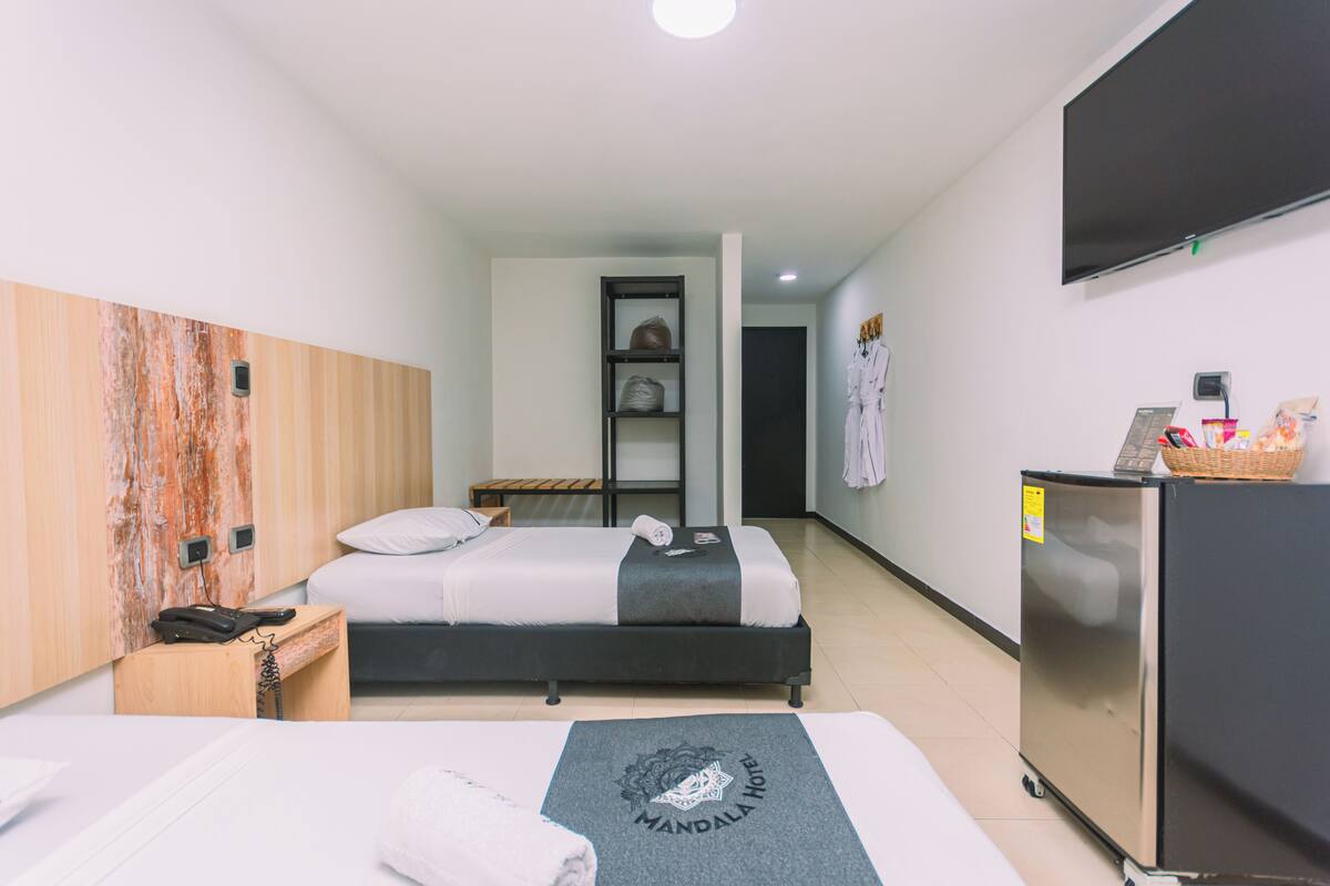 Habitación de hotel con una cama, un escritorio con teléfono, refrigerador y televisor de pared.