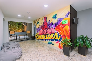 Un vestíbulo moderno con un mural colorido, zona de estar y plantas en macetas.