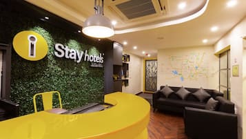 A reception area with a yellow desk, a black sofa, and a green wall with a map.