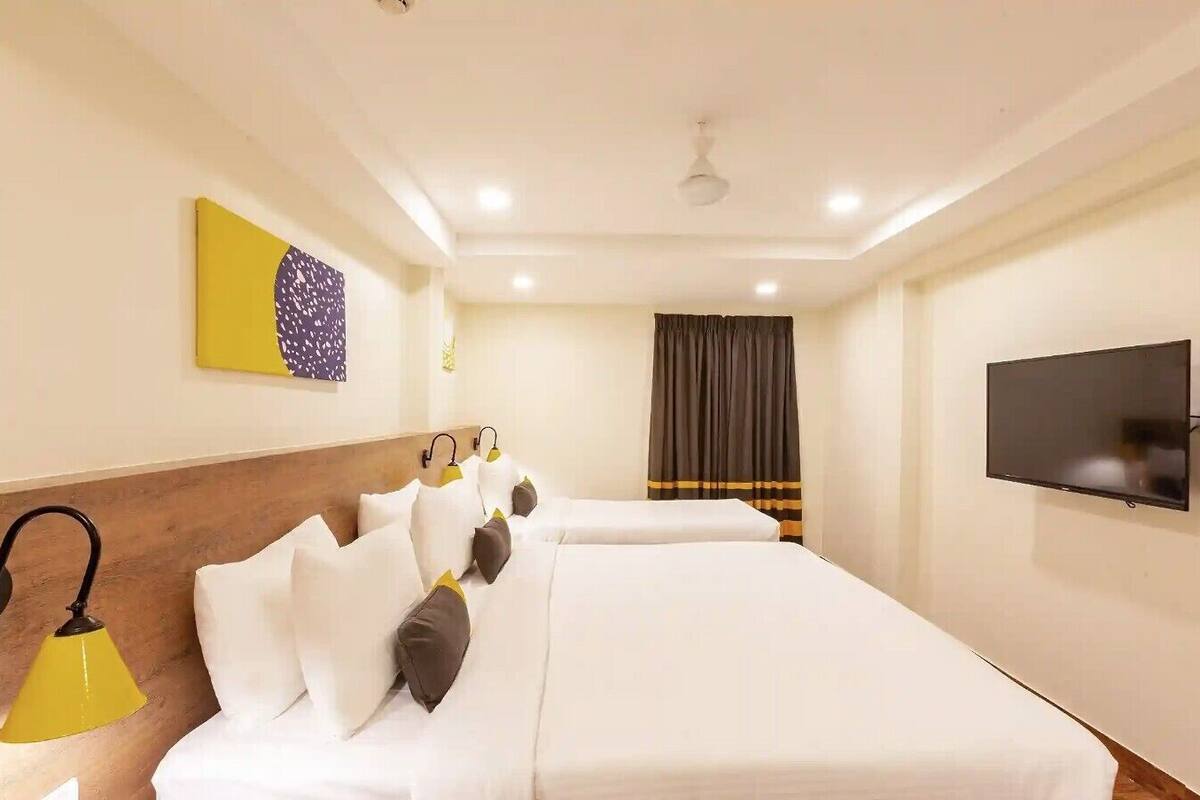 Ein Hotelzimmer mit zwei Betten, einem Flachbildfernseher, einem Deckenventilator und einem Bild an der Wand.