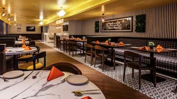 A restaurant with round tables, rectangular booths, and a patterned floor.