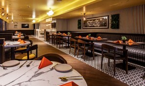Ein Restaurant mit runden Tischen, rechteckigen Sitzbänken und einem gemusterten Boden.