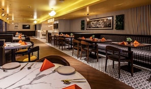 A restaurant with round tables, rectangular booths, and a patterned floor. - Istay Hotels Jubilee Hills Hyderabad by Othpl (Hyderabad)