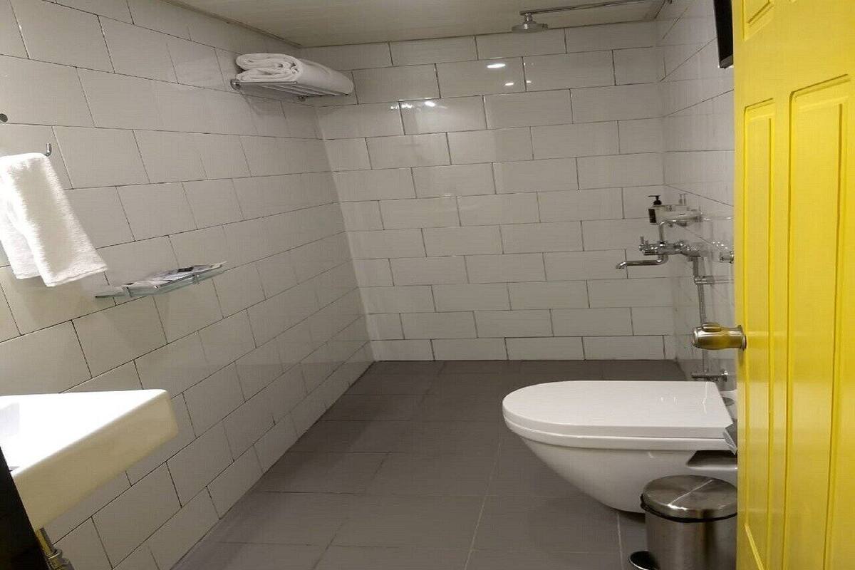 Ein Badezimmer mit weißen Fliesen, einer Toilette, einem Waschbecken und einer Dusche.