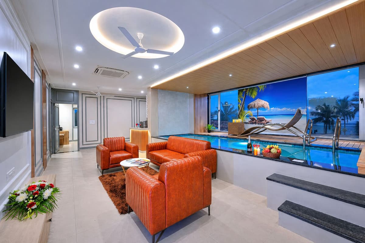 Una sala de estar moderna con piscina, sofás de cuero y un televisor grande.