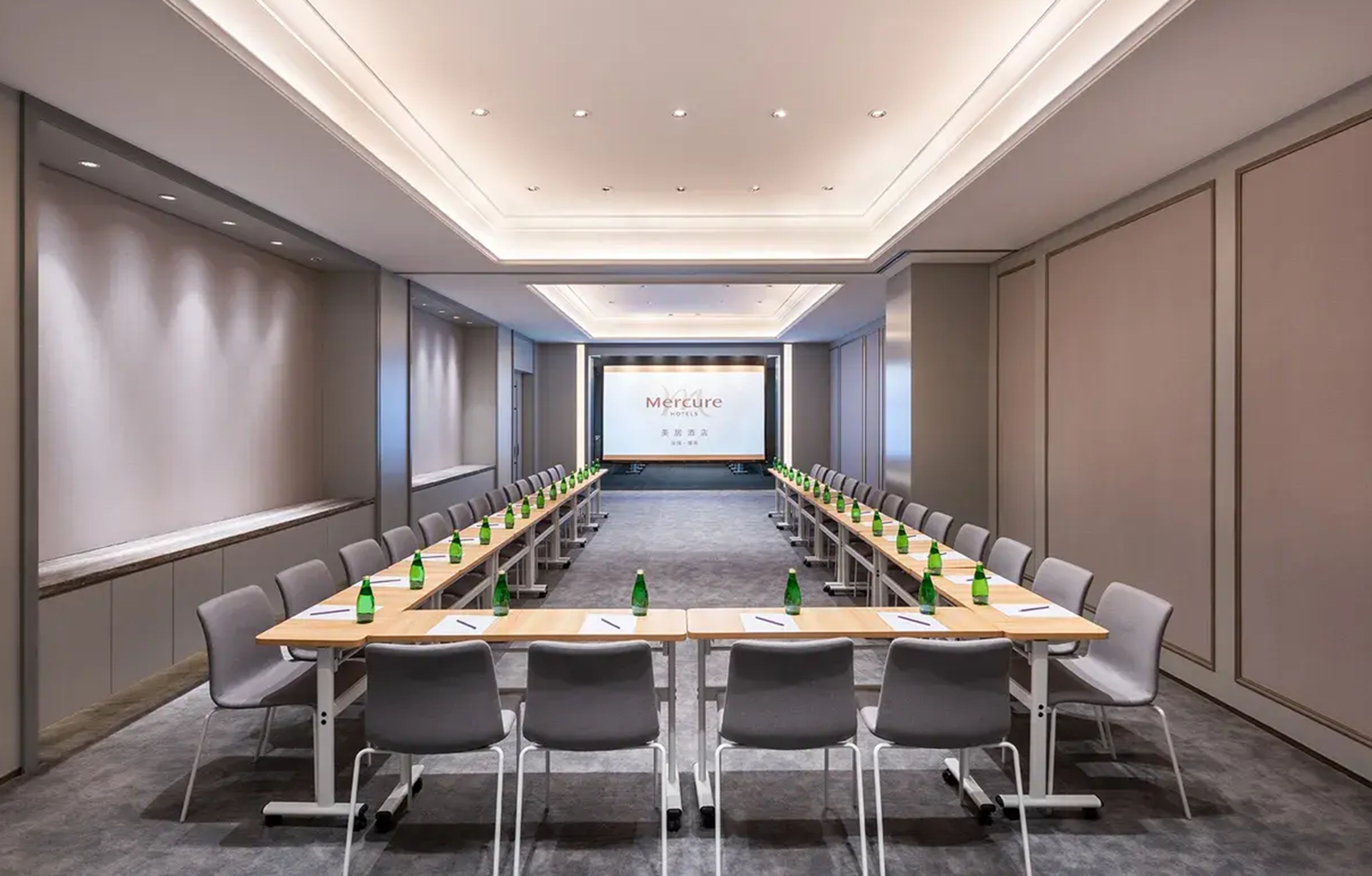 A conference room with a long table, chairs, and a presentation screen.
