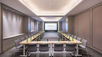 A conference room with a long table, chairs, and a presentation screen.