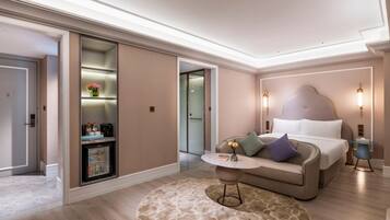 A modern hotel room with a bed, a round coffee table, a sofa, a small table with a vase, and a built-in wardrobe.
