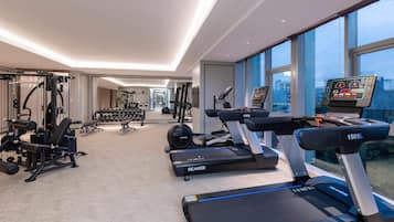 A modern gym with treadmills, weight machines, and a digital screen.