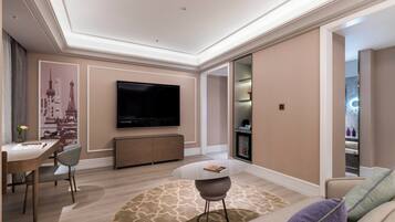 Una sala de estar moderna con un televisor de pantalla plana, un comedor con mesa y sillas, y una zona de estar acogedora con sofá y cojines.