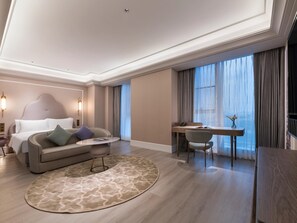 Habitación de hotel moderna con cama, sofá, escritorio y vistas a la ciudad.