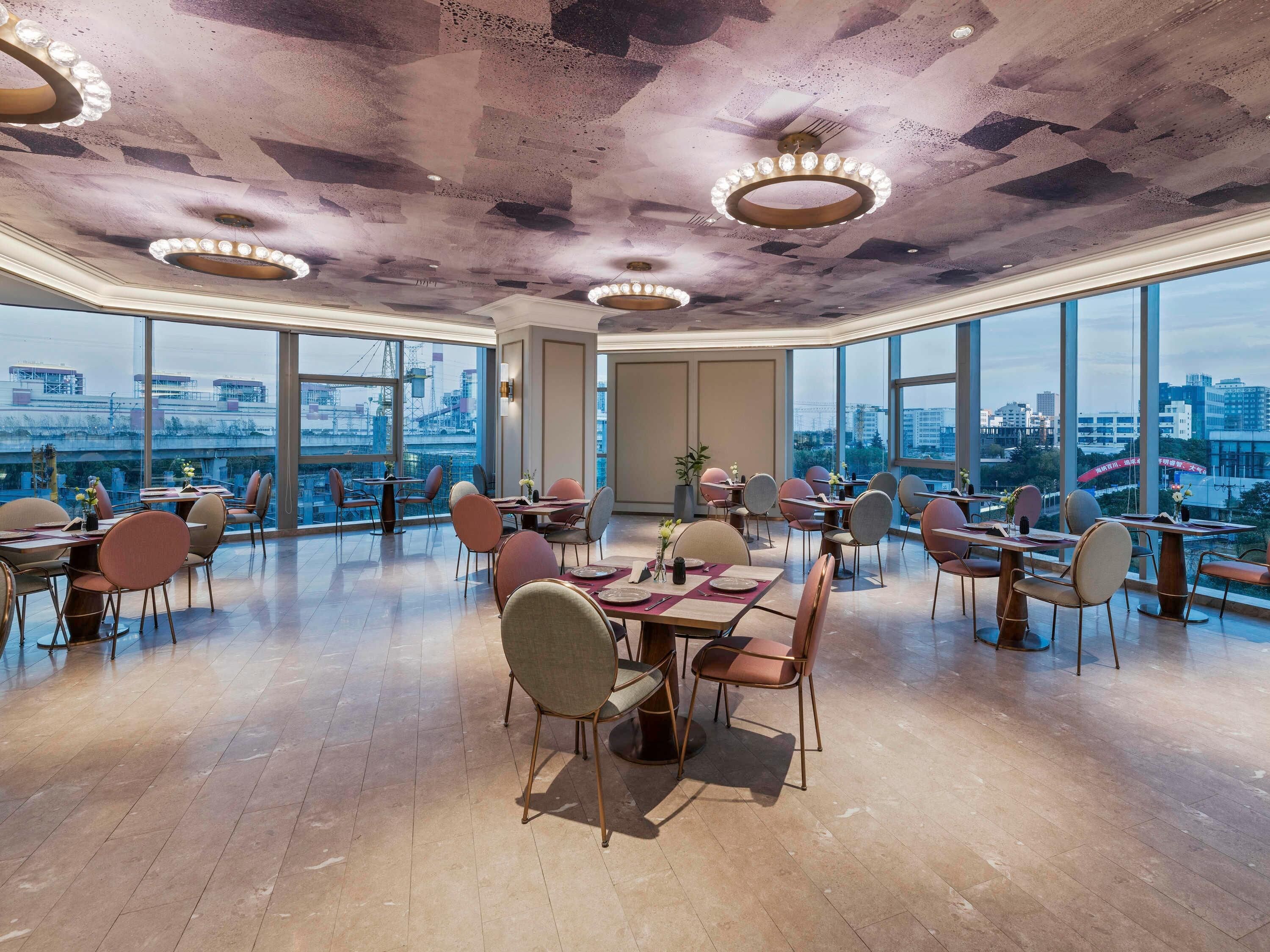 Un comedor amplio con techos altos, ventanas grandes y vistas a la ciudad.