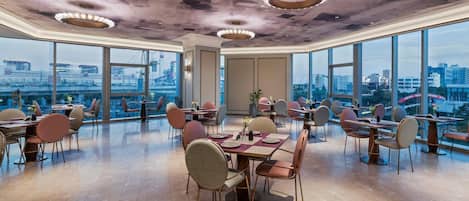 Un comedor amplio con techos altos, ventanas grandes y vistas a la ciudad.