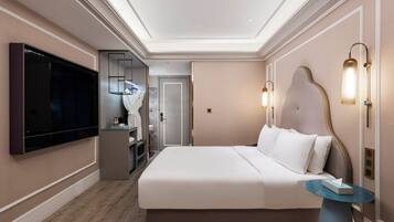Una habitación de hotel moderna con una cama grande, un televisor de pantalla plana, un tocador con espejo y una pequeña mesa.