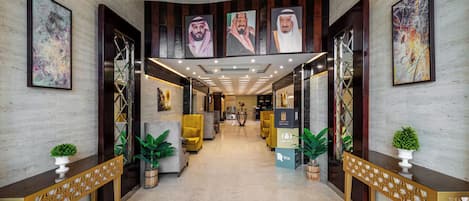 A hotel lobby with a marble floor, modern furniture, and artwork on the walls.