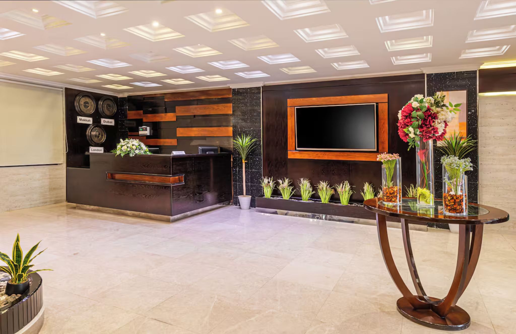 Un espace d’accueil doté d’un bureau moderne, d’un téléviseur à écran plat et de plantes décoratives.