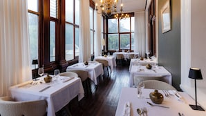 A restaurant with multiple tables, chandeliers, and large windows. - The Cape Town Club (Cape Town)