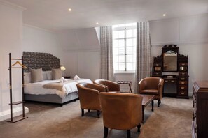 A hotel room with a bed, two armchairs, a small table, a dresser, and a mirror. - The Cape Town Club (Cape Town)