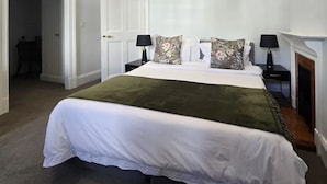 A neatly made bed with a white and green bedspread, two black nightstands with lamps, and a white door in the background. - The Cape Town Club (Cape Town)