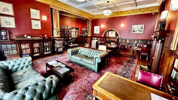 A library with leather sofas, bookshelves, and a red carpet. - The Cape Town Club (Cape Town)