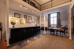 A spacious room with a black bar, multiple chairs, a dining table, and a staircase leading to an upper level. - The Cape Town Club (Cape Town)