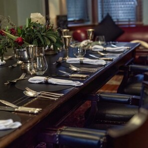 A long dining table set with silverware, plates, and a vase of flowers. - The Cape Town Club (Cape Town)