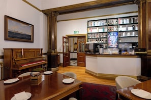 A hotel lobby with a piano, a bar area with a television, and a bookshelf with various items. - The Cape Town Club (Cape Town)