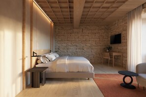 A bedroom with a stone wall, a bed, a TV mounted on the wall, a small table, and a chair. - Castilla Termal Palacio De Avellaneda (Penaranda de Duero)